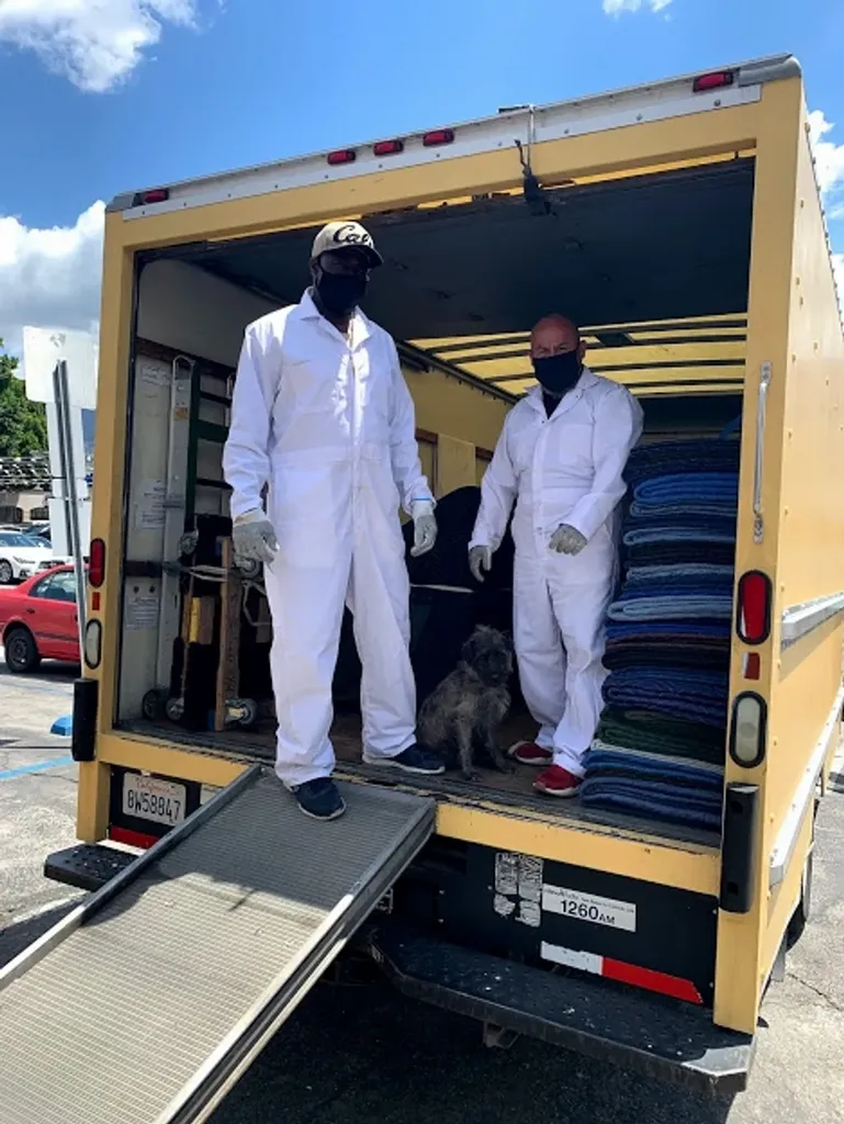 The Jose Express crew in white coveralls and gloves at the truck, moving blankets stacked behind them